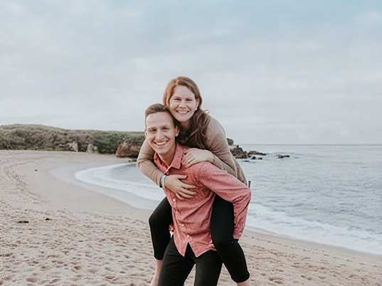 playful-couple-piggyback-seaside